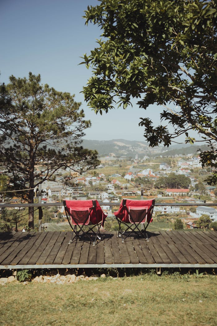Peaceful mountain view with two red camping chairs overlooking Đà Lạt, perfect for relaxation.